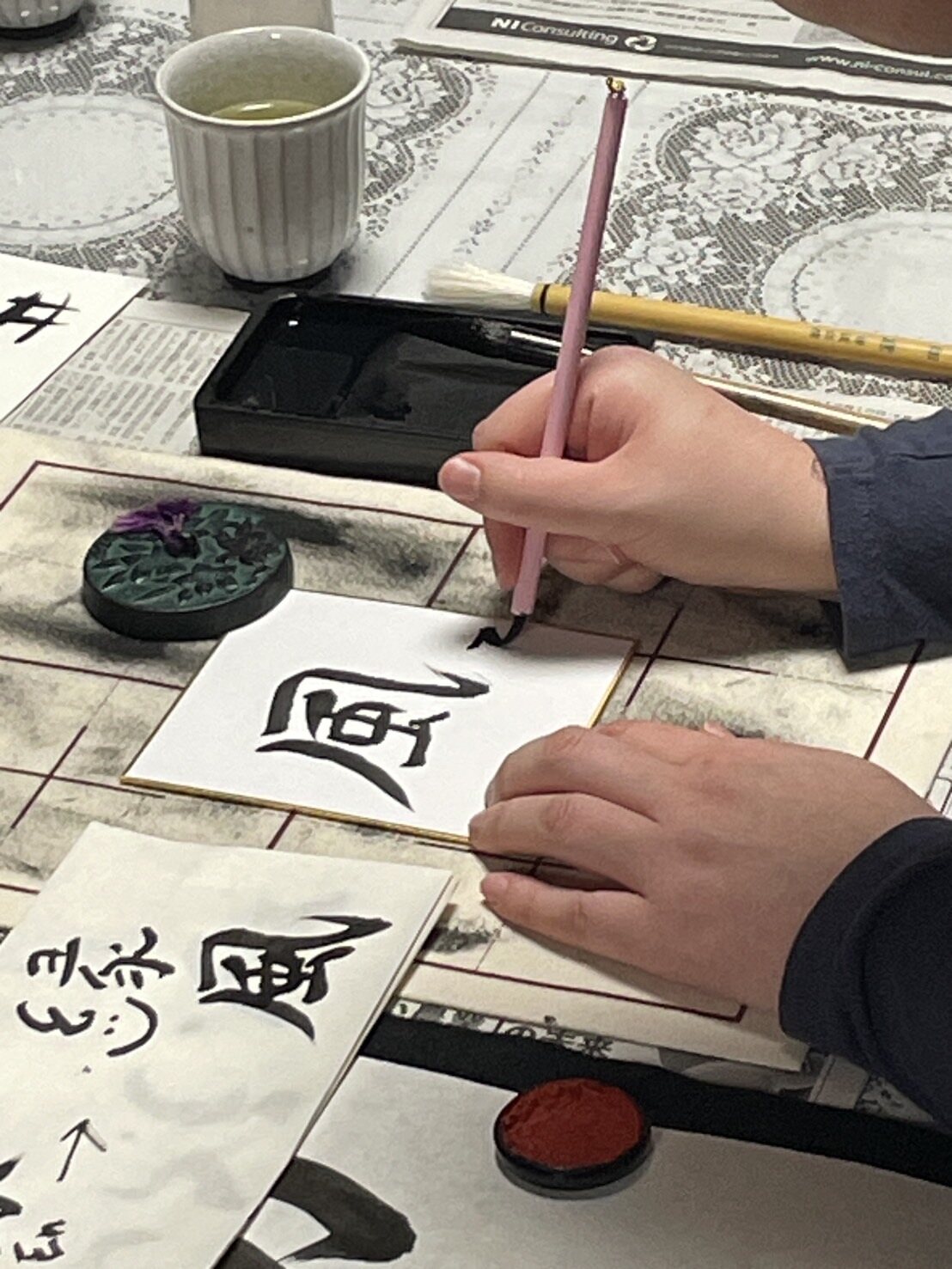Hands creating Japanese calligraphy